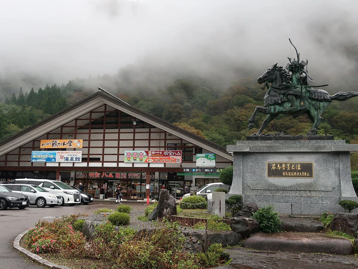 山を背景にした道の駅 明宝の施設外観と名馬磨墨之像