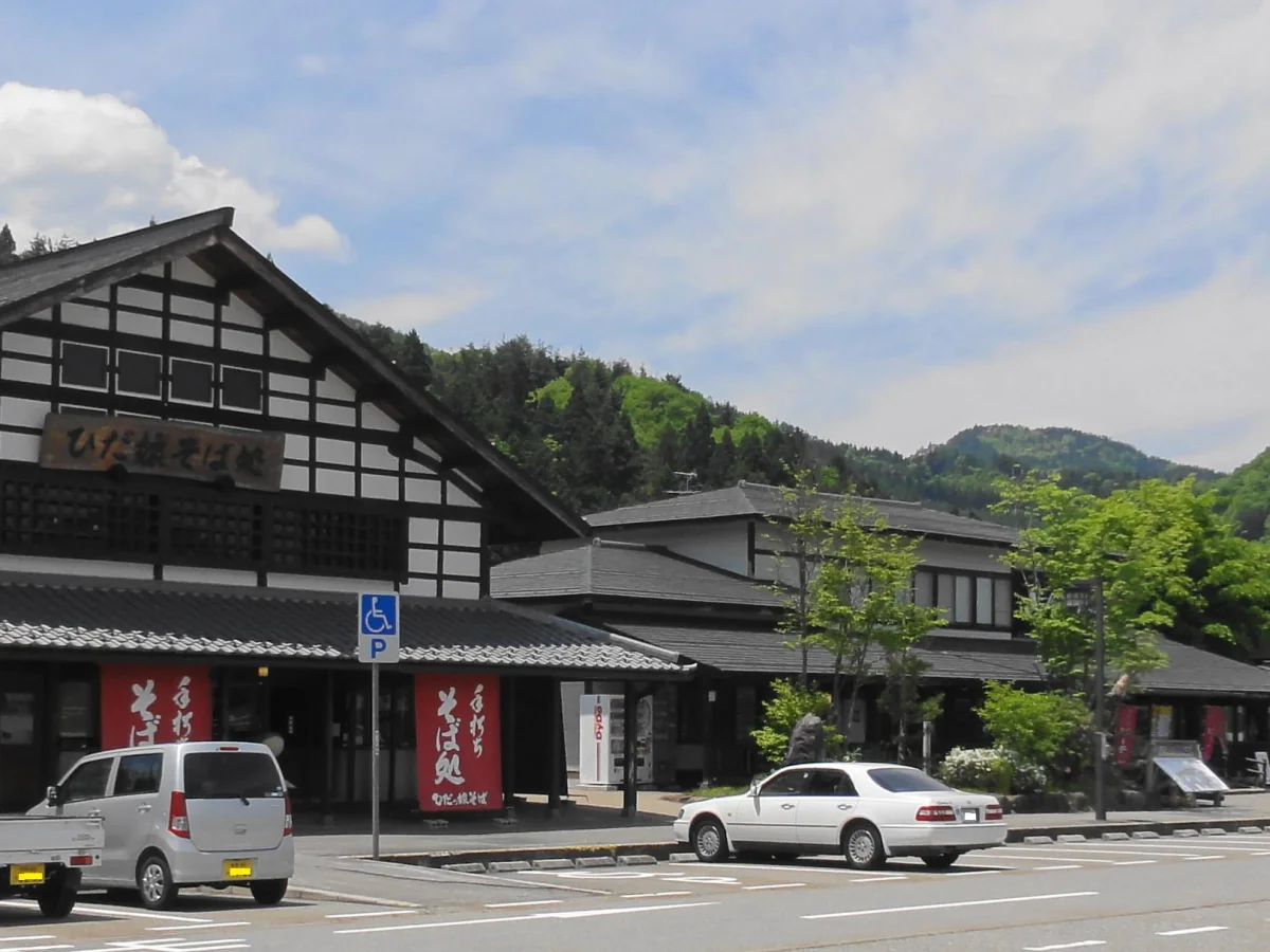 山を背景にした道の駅 アルプ飛騨古川の施設外観と駐車場