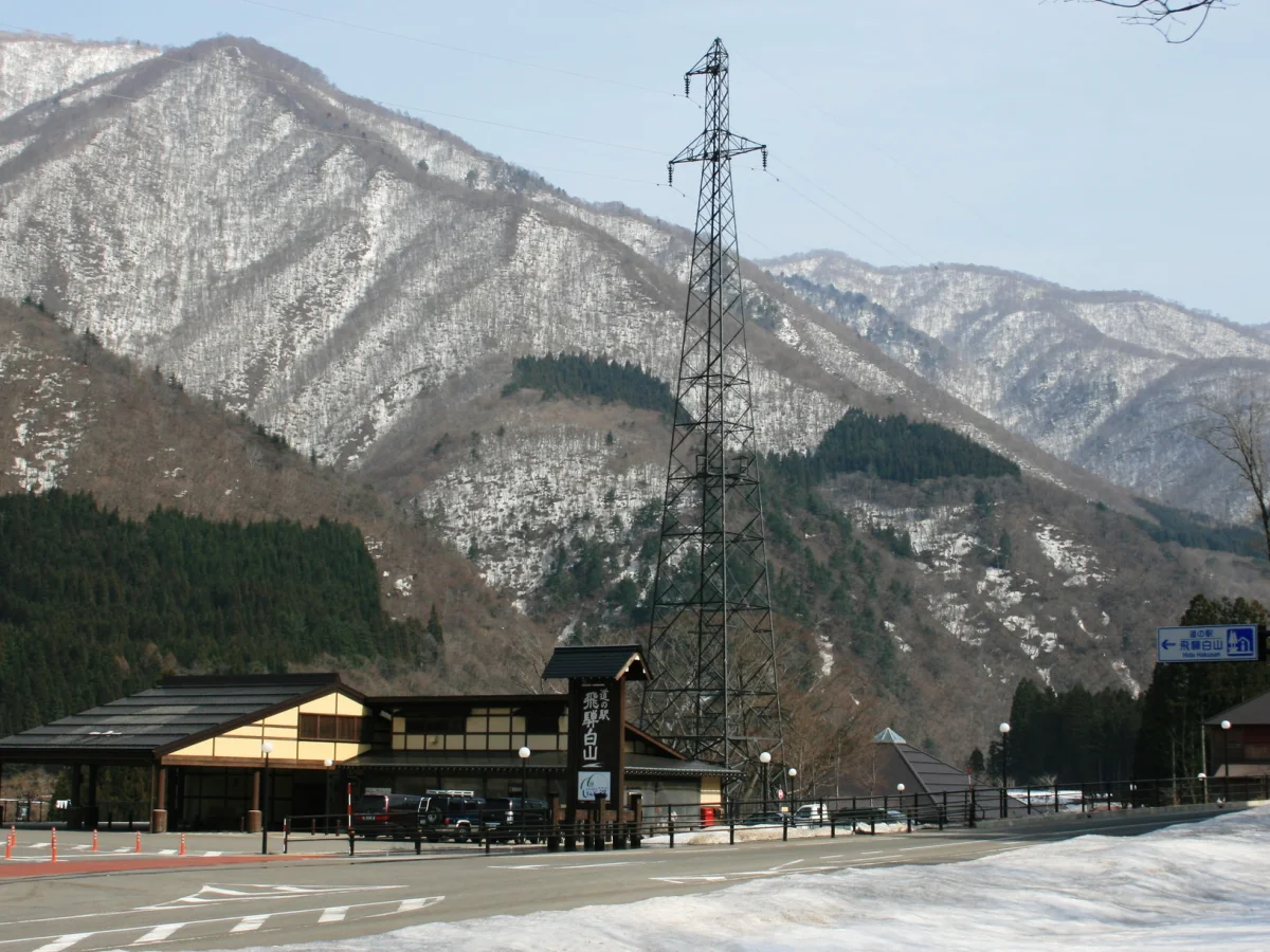 雪の残る山々を背景にした道の駅 飛騨白山の外観